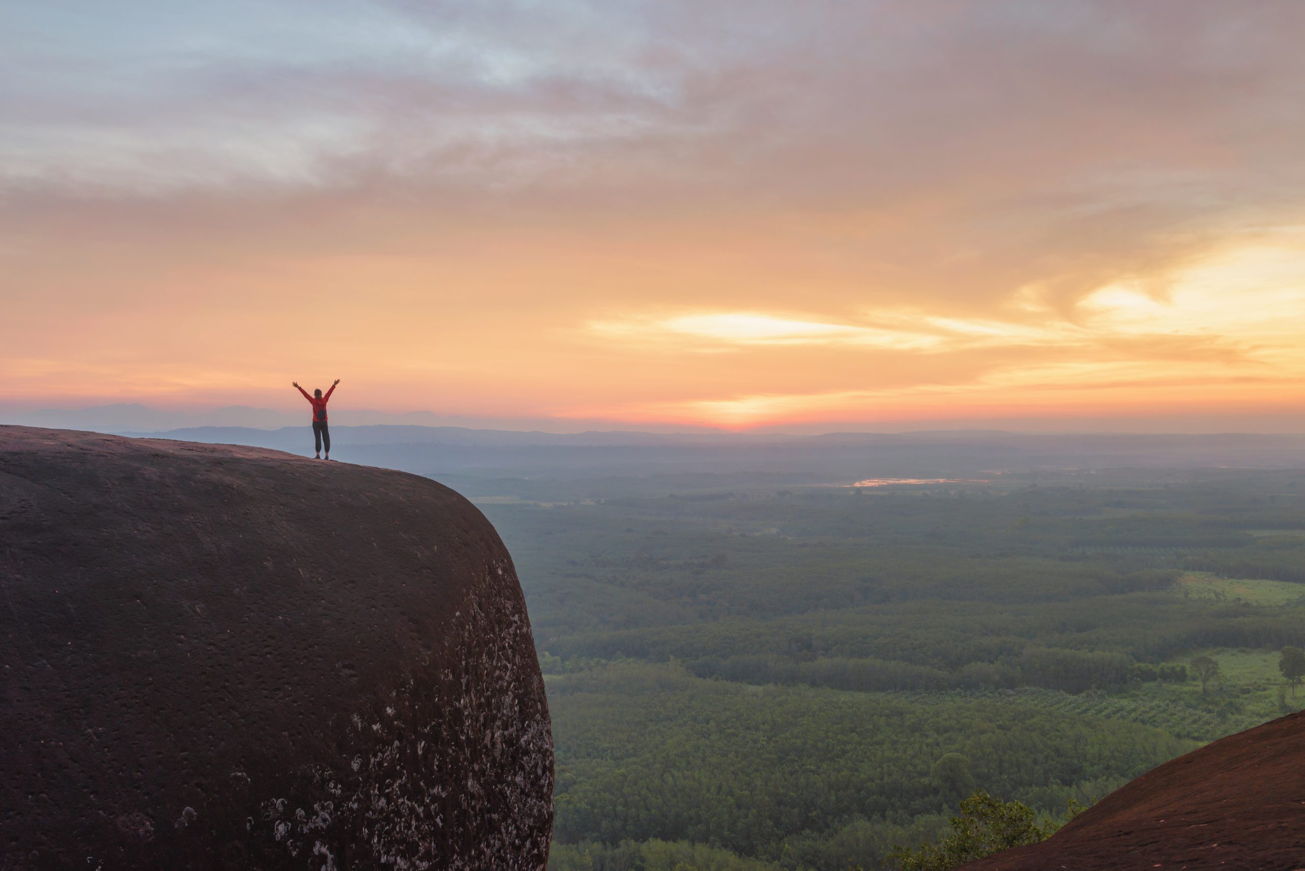 Person standing on rock on top of mountain