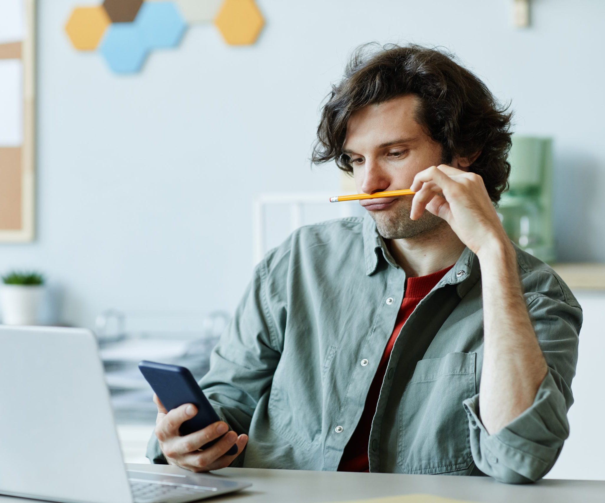 Bored Young Man in Office Using Phone