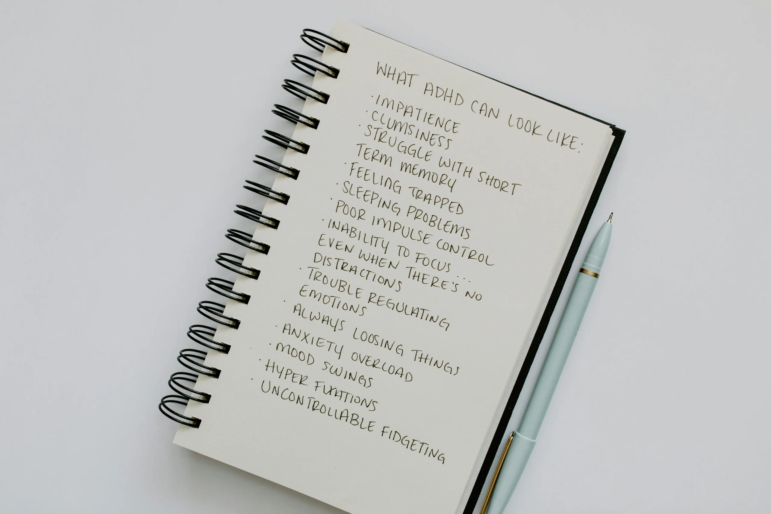 Notepad displaying a common list of adult ADHD symptoms, including difficulty focusing, forgetfulness, and trouble organising daily tasks.